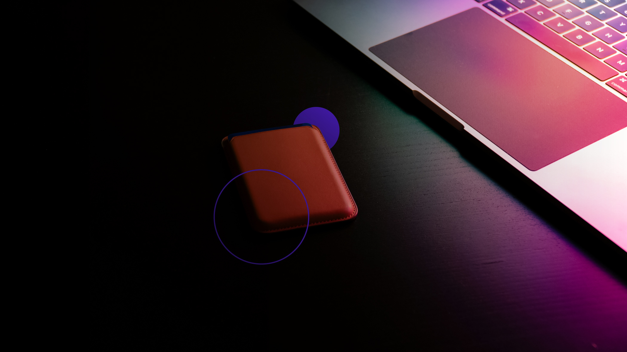 A red wallet lies on the table next to a laptop
